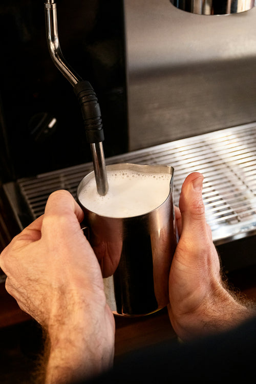Milk frother wand whipping fresh milk foam
